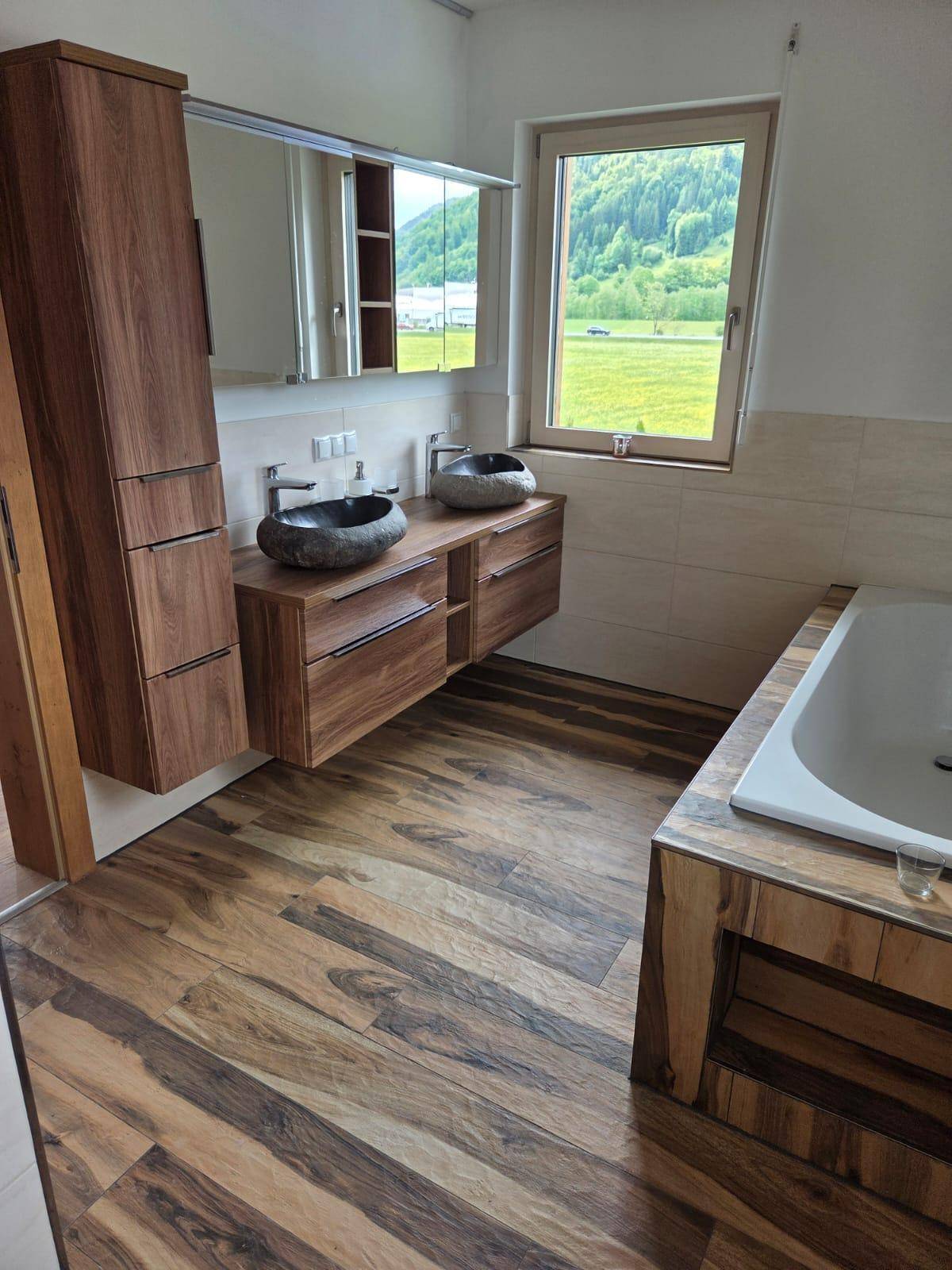 Modernes Badezimmer mit Doppelwaschbecken, Badewanne und Blick auf die Landschaft.