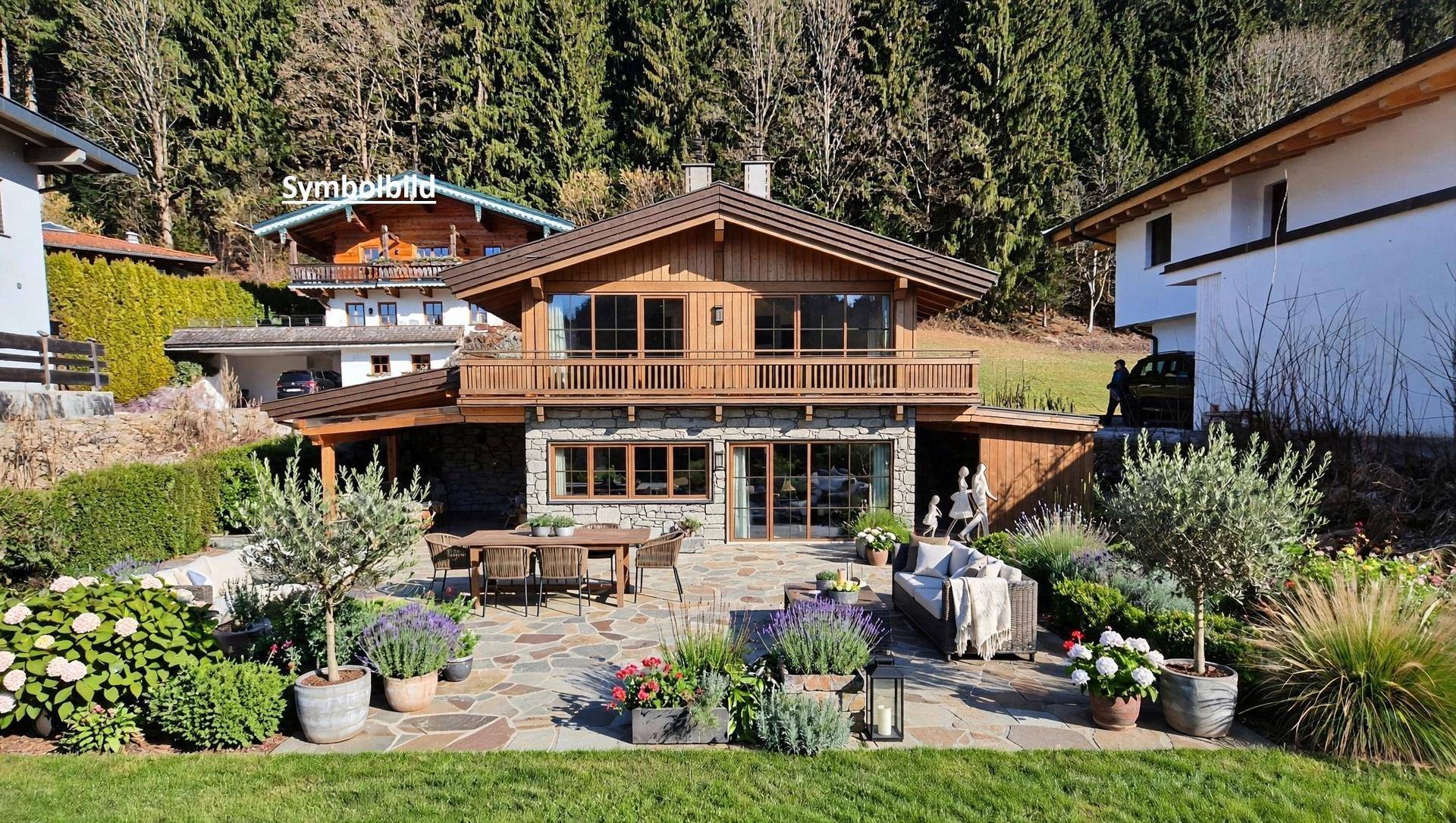 Helles Chalet mit großer Steinterrasse und Garten, umgeben von Wald und Natur bei Tageslicht.