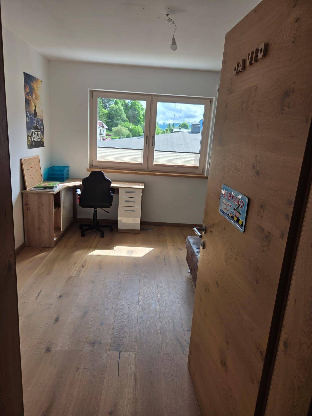 Helles Arbeitszimmer mit Holzboden, Schreibtisch und Blick ins Grüne.