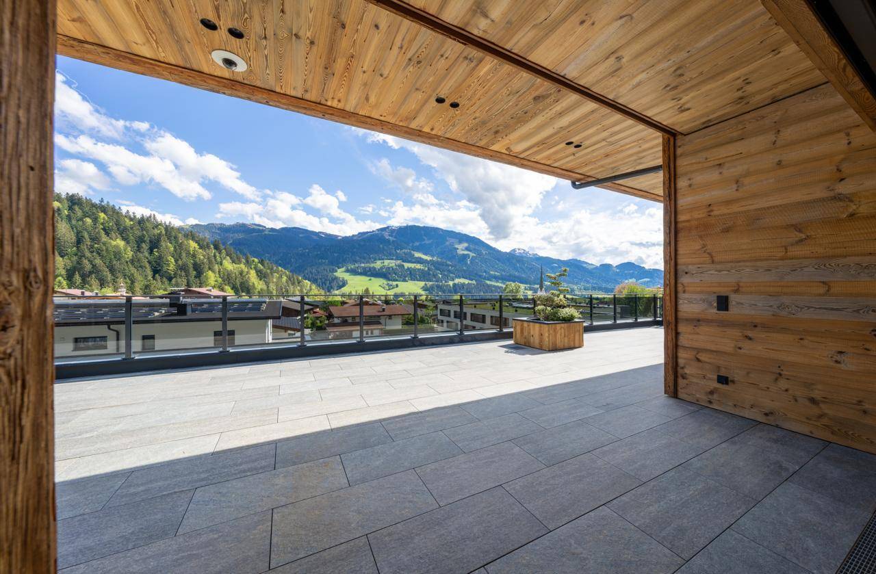 Überdachte Terrasse mit Holzelementen und weitem Blick auf die umliegende Natur.