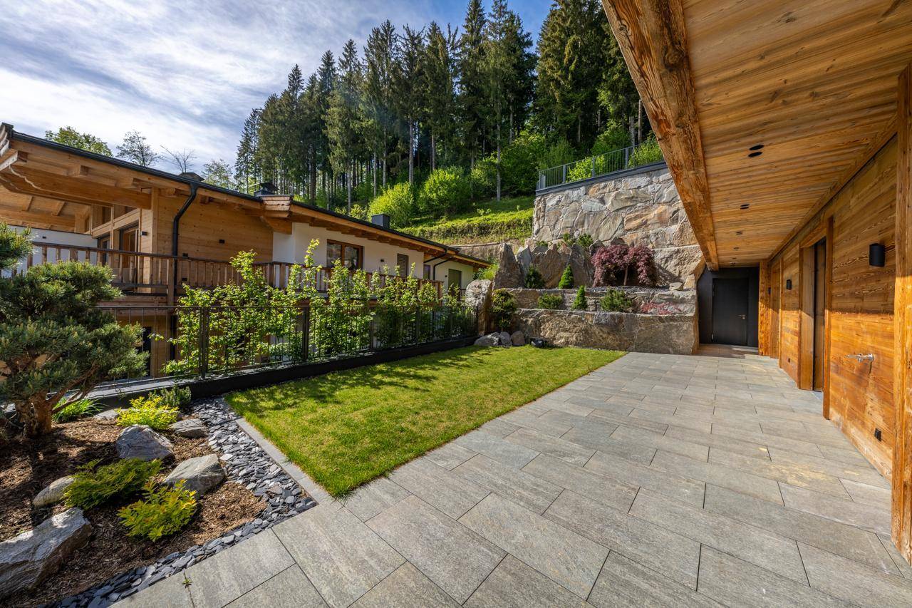 Gepflegter Gartenbereich mit Rasenfläche, Steingarten und natürlicher Felswand.