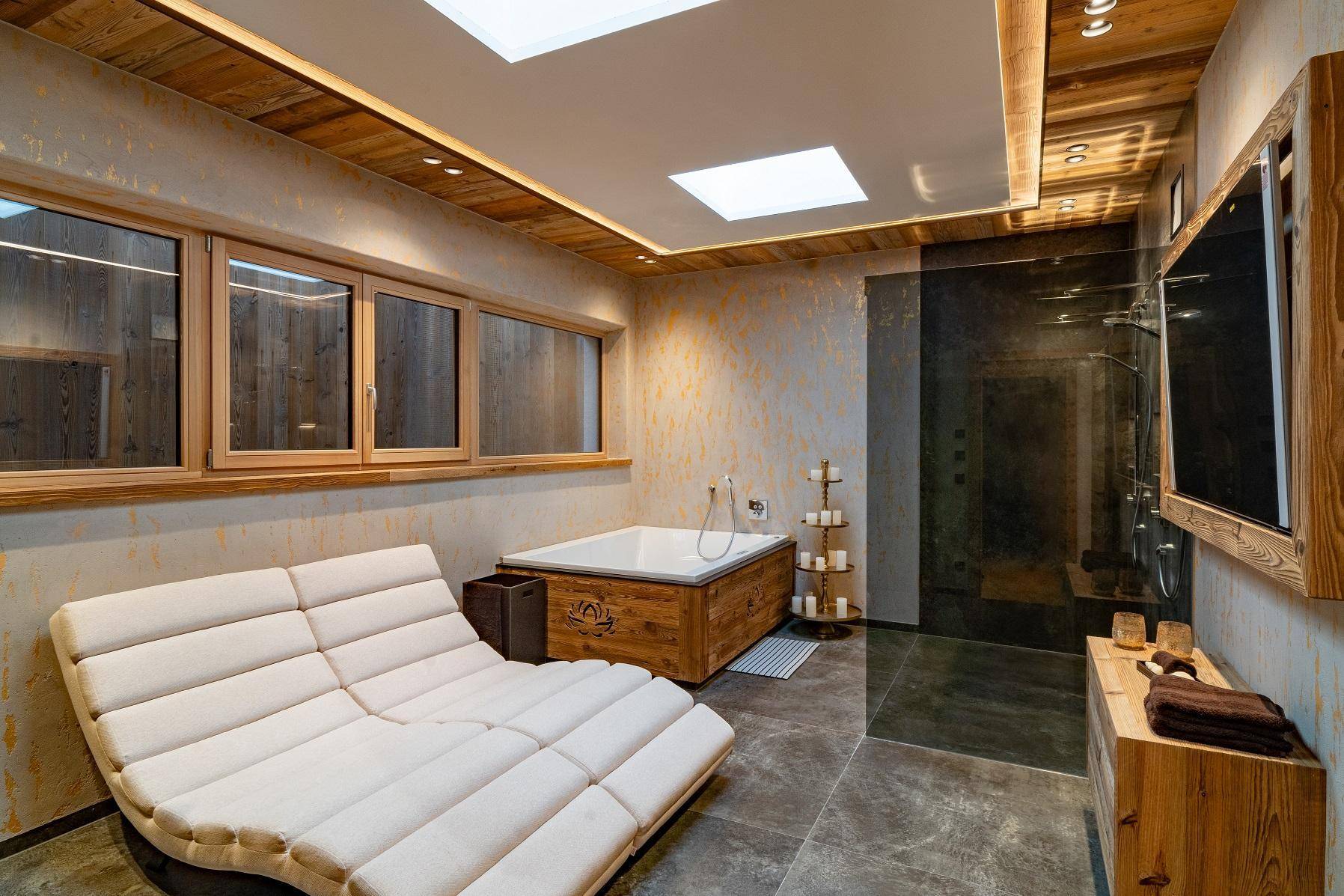 Luxuriöses Spa-Badezimmer mit Badewanne, Dusche und Liegefläche zur Entspannung.