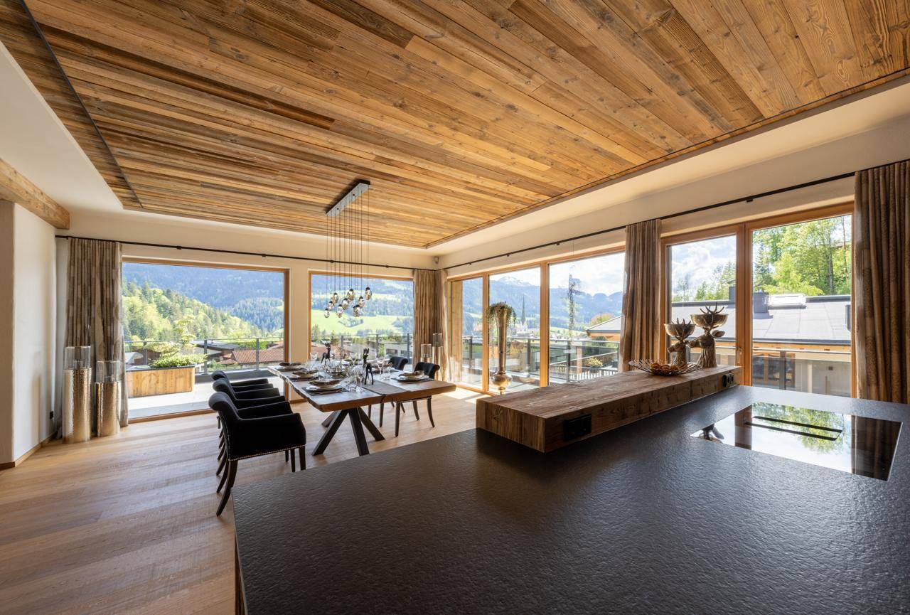 Eleganter Essbereich mit Holzbalkendecke, großen Fenstern und Bergblick.