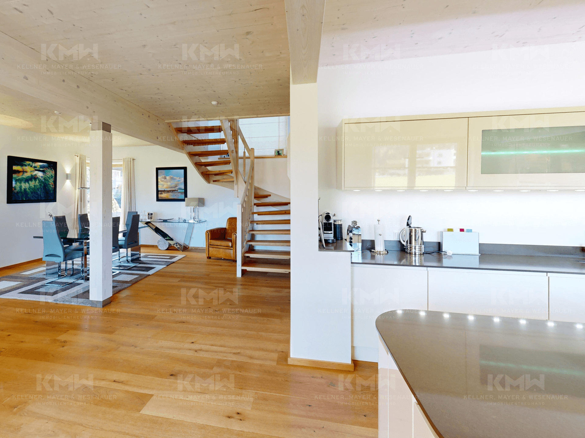 Offener Wohnbereich mit Holztreppe, Parkettboden und Blick in die moderne Küche.