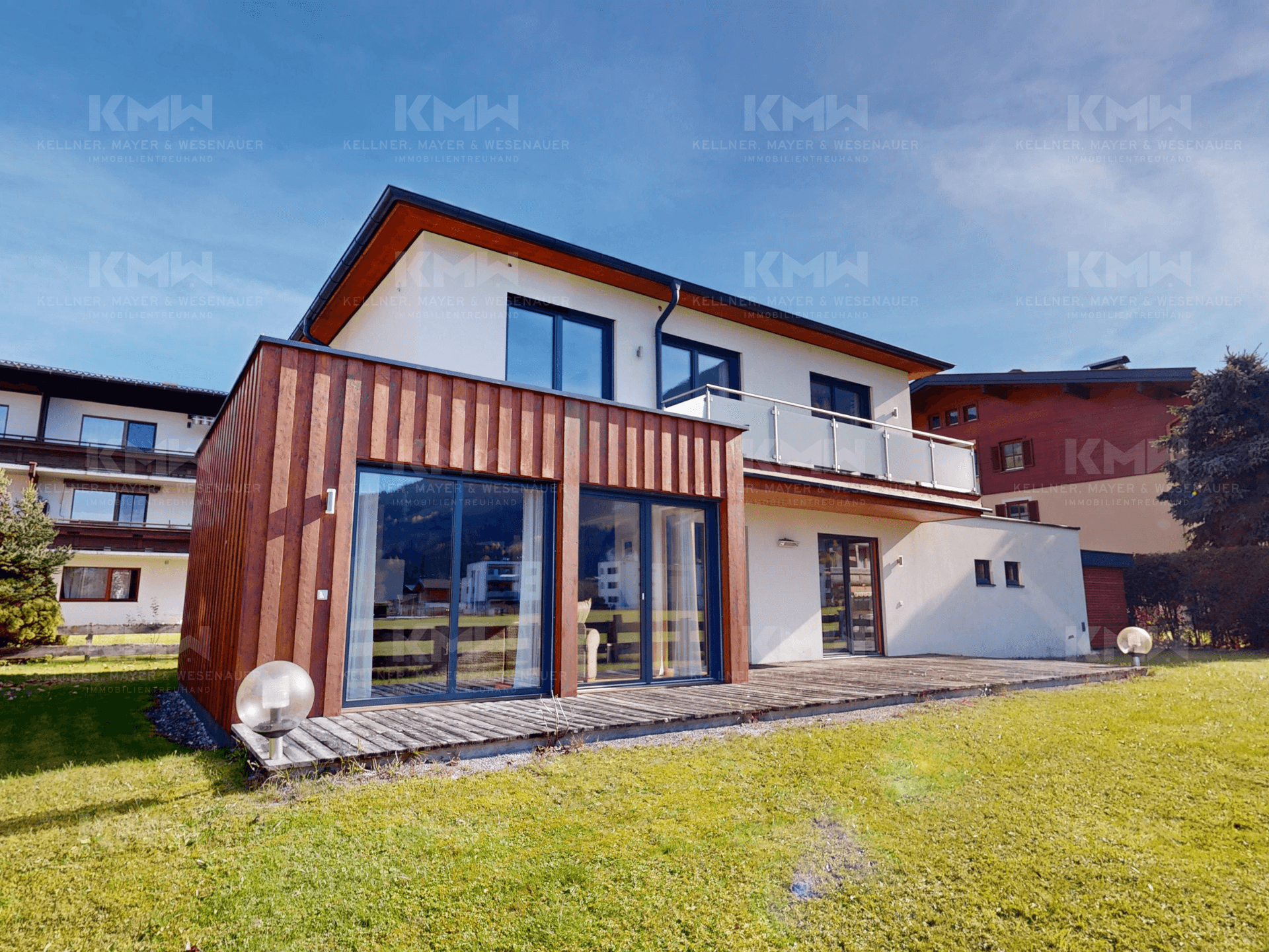 Ansicht des modernen Hauses mit Holzverkleidung, großer Terrasse und Zugang zum Garten.