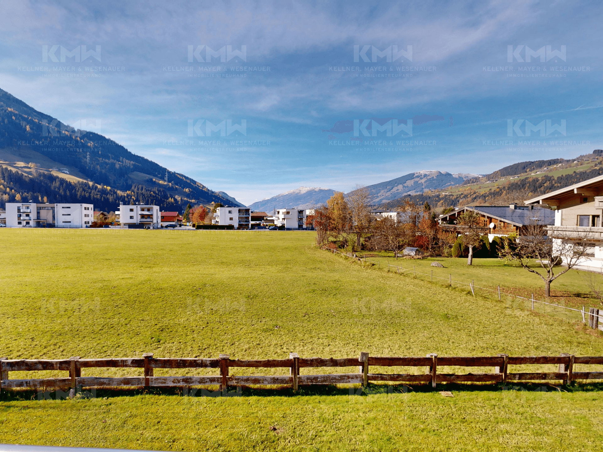 Weitläufige grüne Wiesen mit Blick auf die Berge und die umliegende Bebauung.