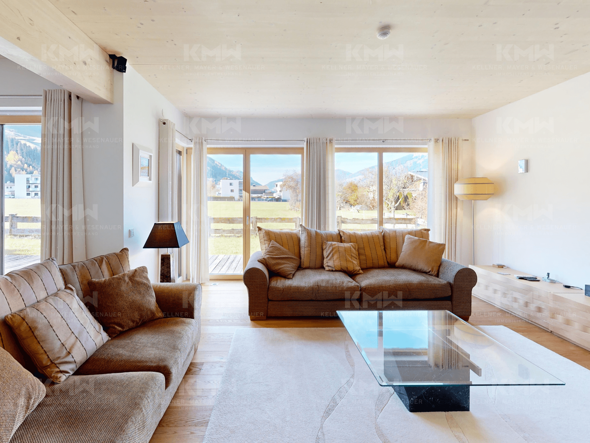Gemütliches Wohnzimmer mit bequemen Sofas, Holzboden und großen Fenstern mit Weitblick.