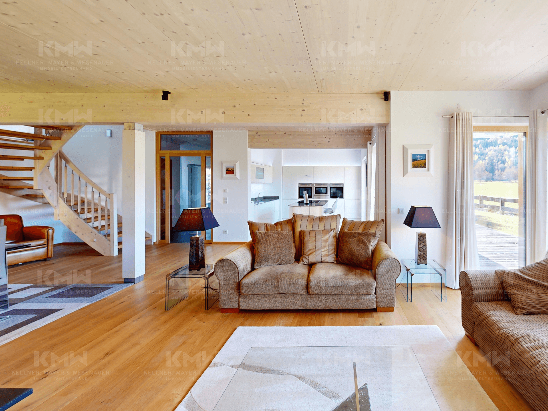 Geräumiges Wohnzimmer mit Holzbalkendecke, Parkettboden und offener Verbindung zur Küche.