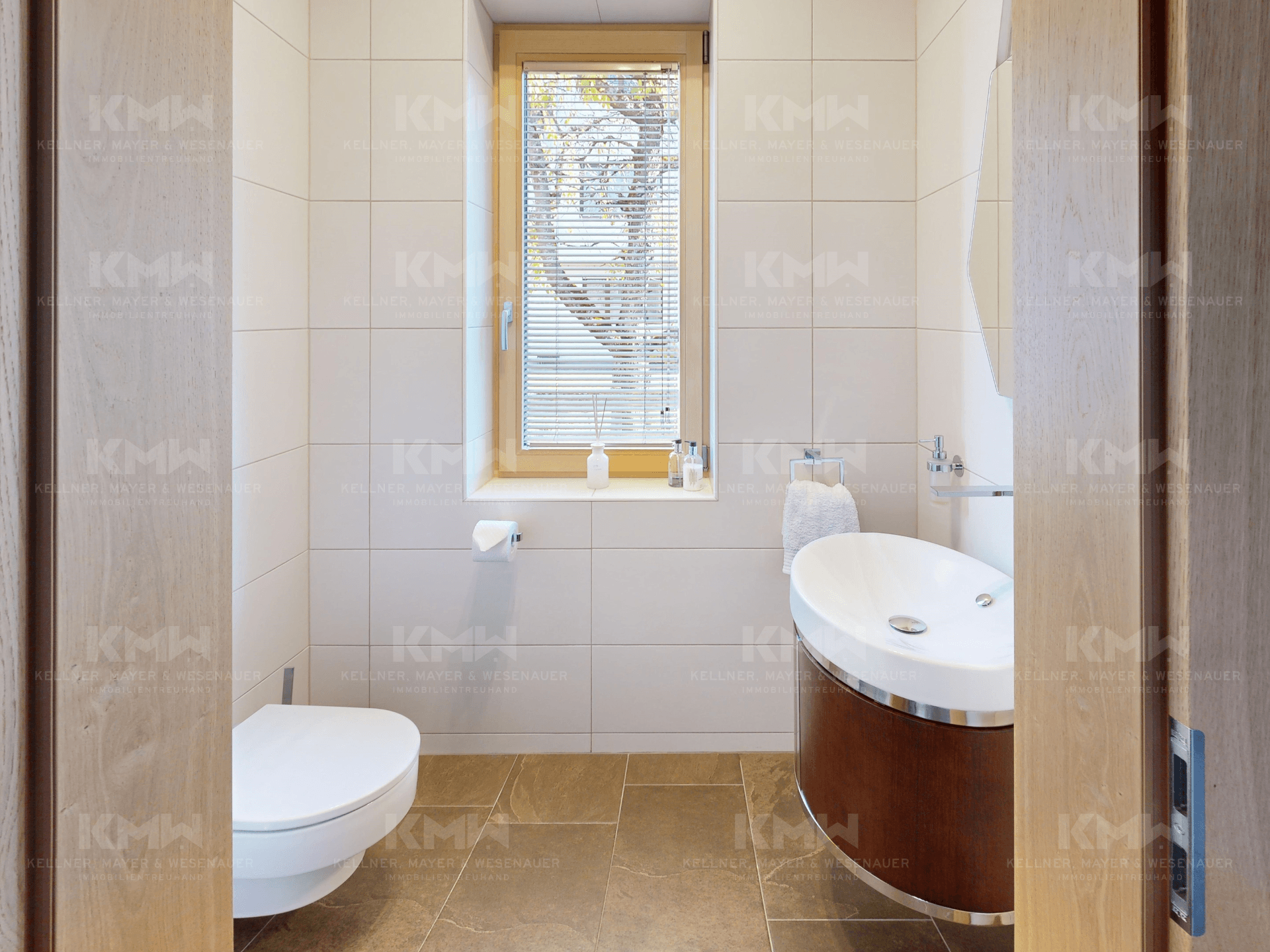 Stilvolles Gäste-WC mit modernem Waschbecken, Wand-WC und Fenster für Tageslicht.