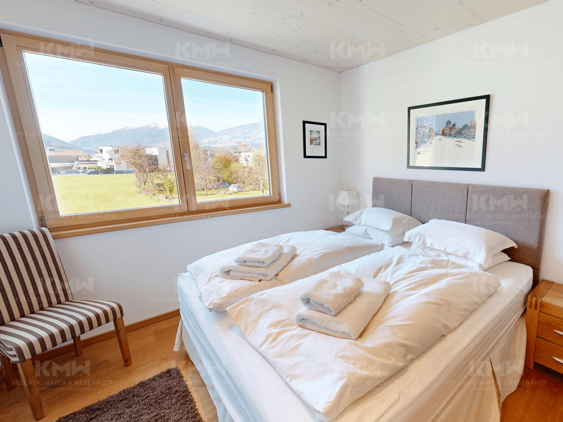 Komfortables Schlafzimmer mit Doppelbett, Holzboden und großen Fenstern mit Bergblick.