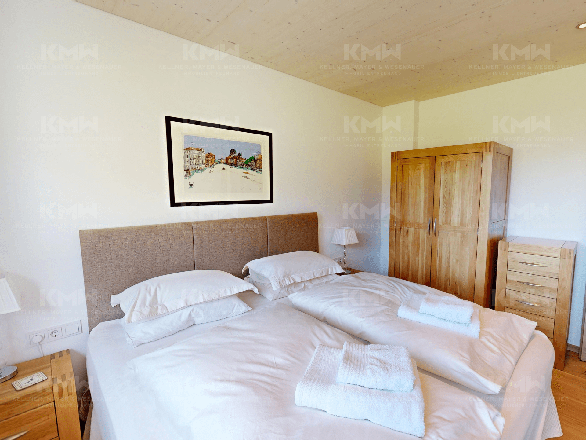 Schlafzimmer mit Doppelbett, Holzboden und einem Holzschrank für Stauraum.