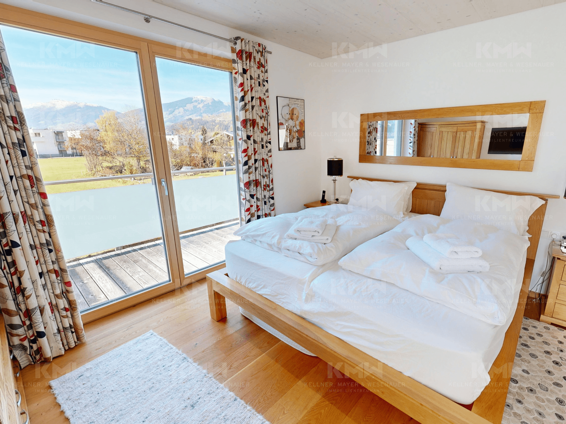 Helles Schlafzimmer mit Doppelbett, Holzboden und direktem Zugang zum Balkon.