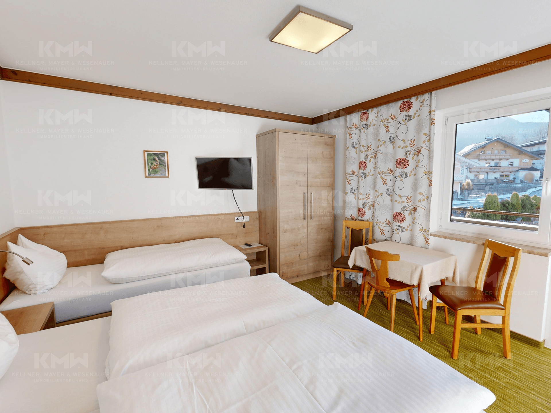 Geräumiges Schlafzimmer mit mehreren Betten, Holzwänden und Blick auf die umliegende Landschaft.