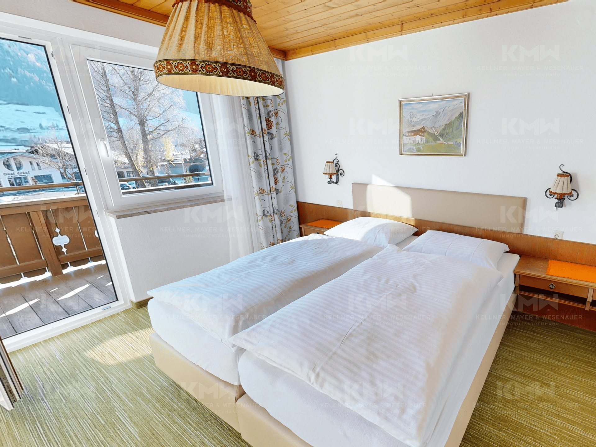 Gemütliches Schlafzimmer mit Holzbalkendecke, Teppichboden und Balkonzugang mit Bergsicht.