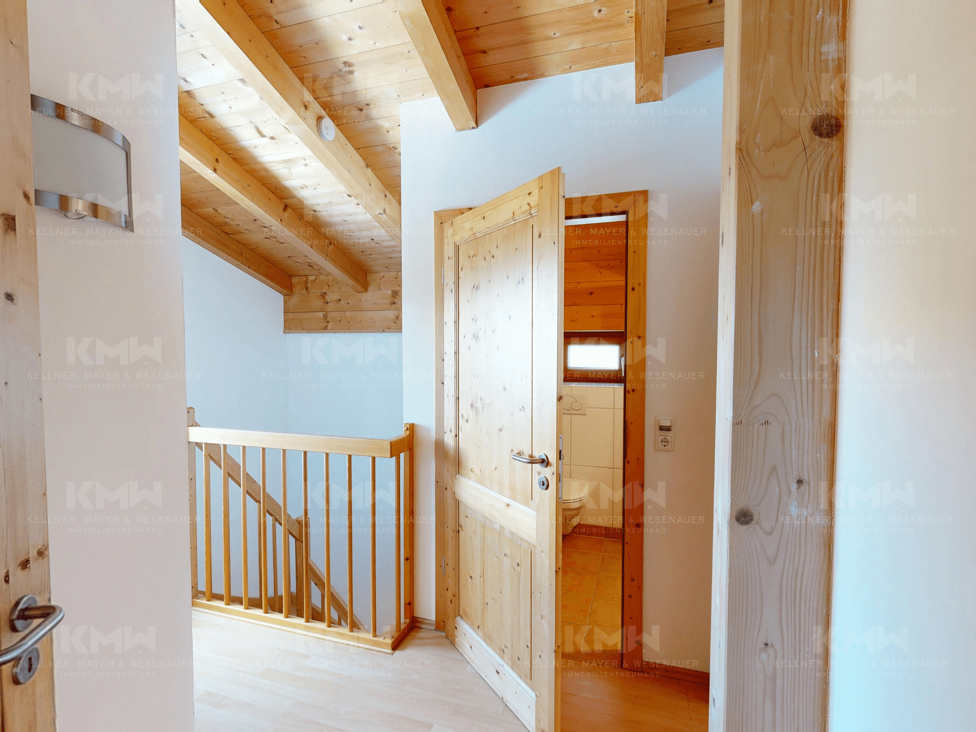 Heller Flur im Obergeschoss mit Holzbalkendecke und Zugang zu weiteren Räumen.