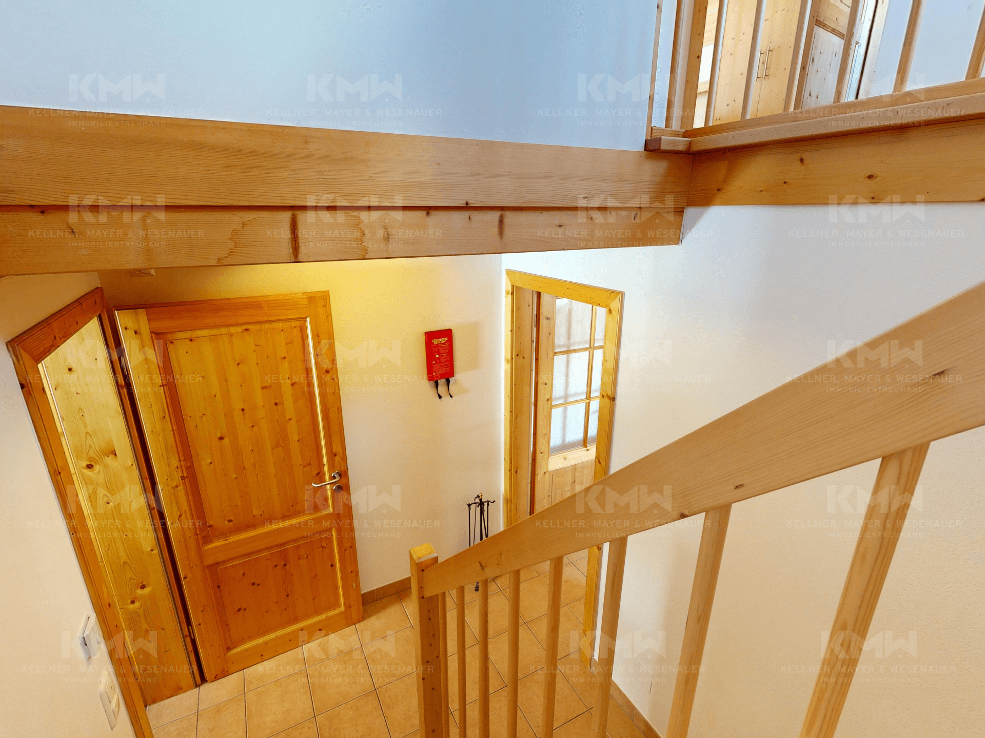 Treppenhaus mit Holzgeländer und Holztüren, das die verschiedenen Ebenen des Hauses verbindet.