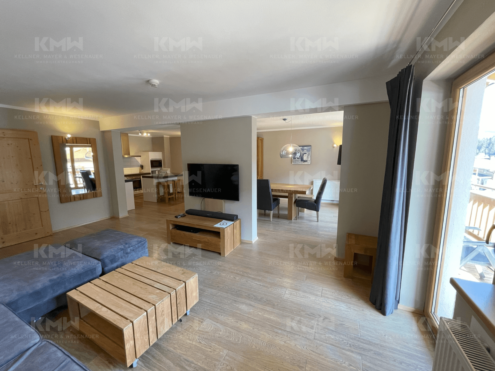 Offener Wohnbereich mit bequemer Couch, Holztisch und Blick auf den Essbereich und die Küche.