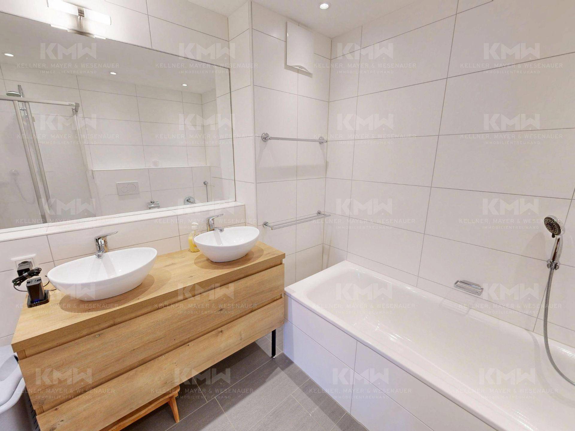 Geräumiges Badezimmer mit Doppelwaschbecken, Badewanne und großem Spiegel in modernem Stil.