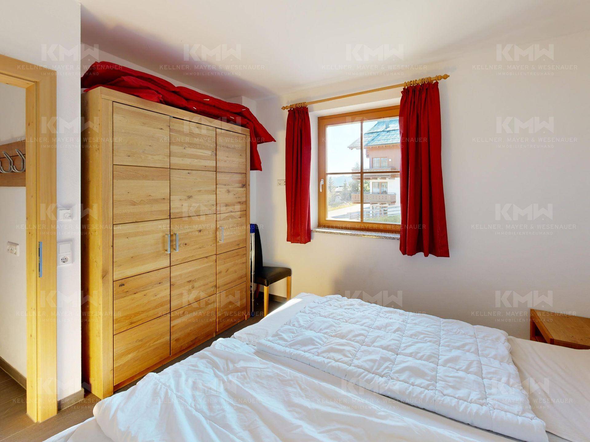 Gemütliches Schlafzimmer mit großem Holzschrank und Fenster, das einen Blick nach draußen bietet.