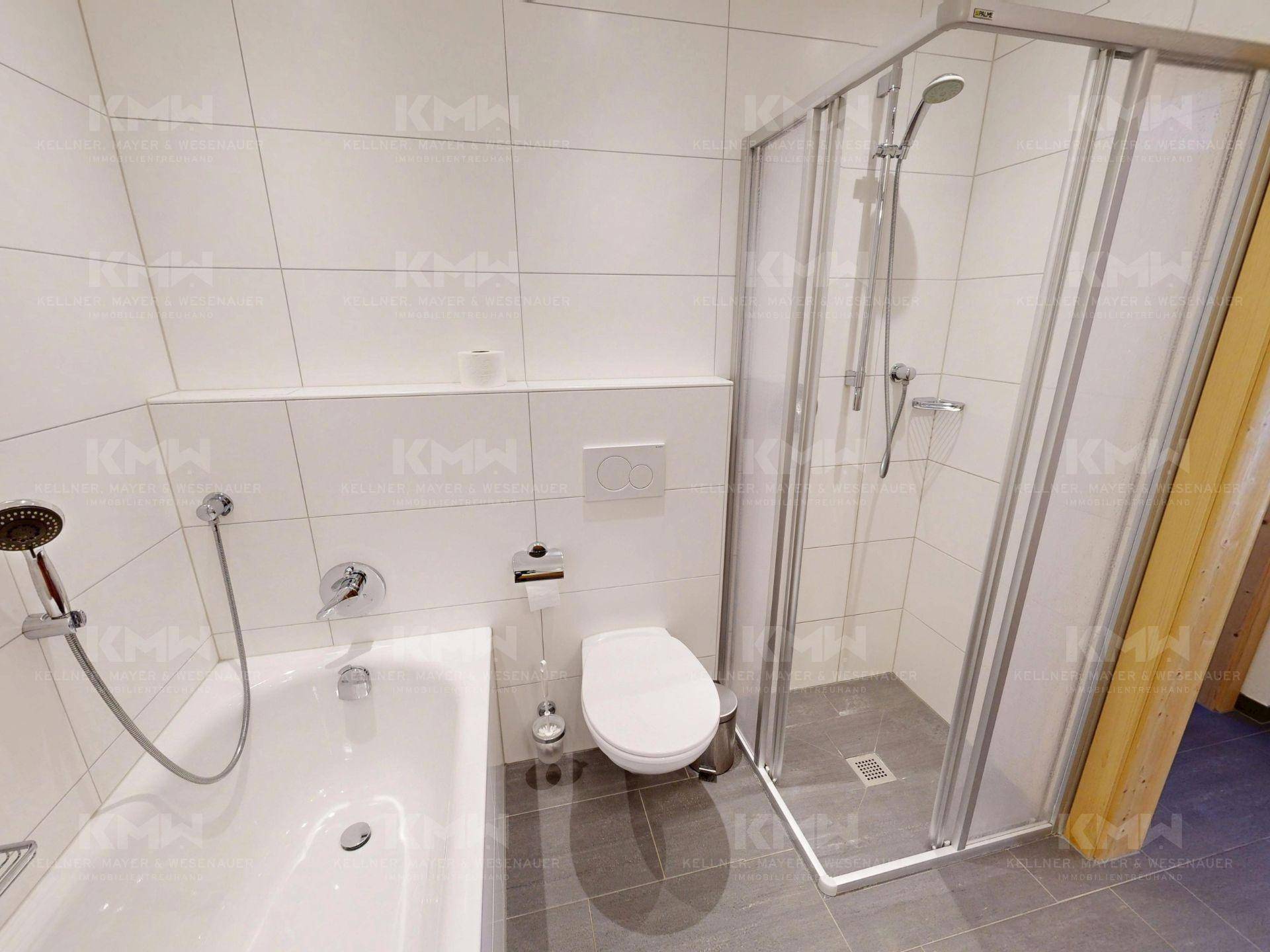 Modernes Badezimmer mit Badewanne, Duschkabine und wandhängendem WC in hellen Fliesen.