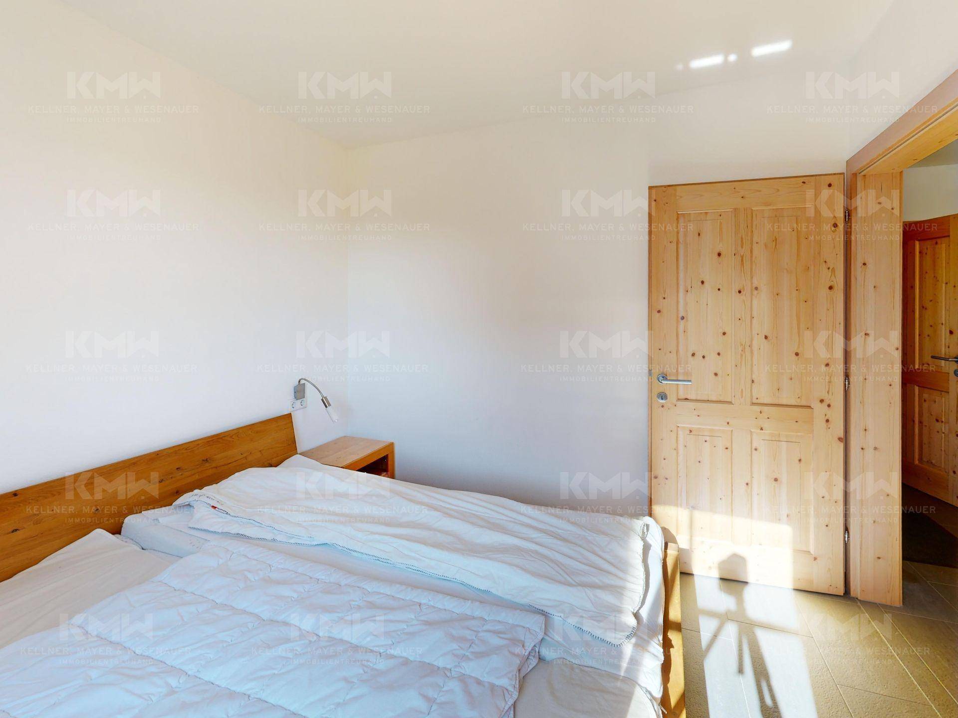 Helles Schlafzimmer mit Doppelbett und Holztüren, das eine warme und einladende Atmosphäre schafft.