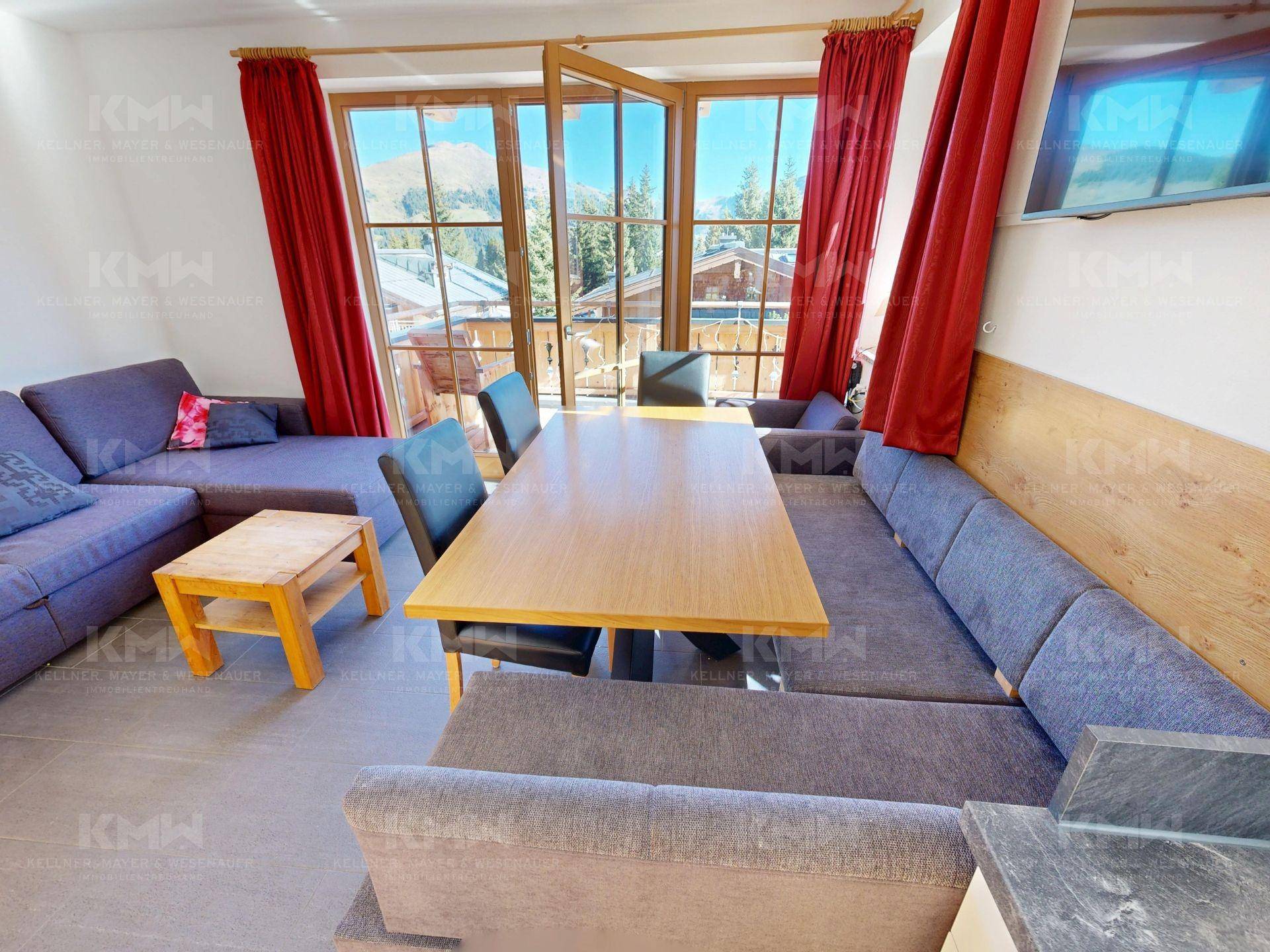 Gemütlicher Wohn-Essbereich mit Zugang zum Balkon und Panoramablick auf die Berge.
