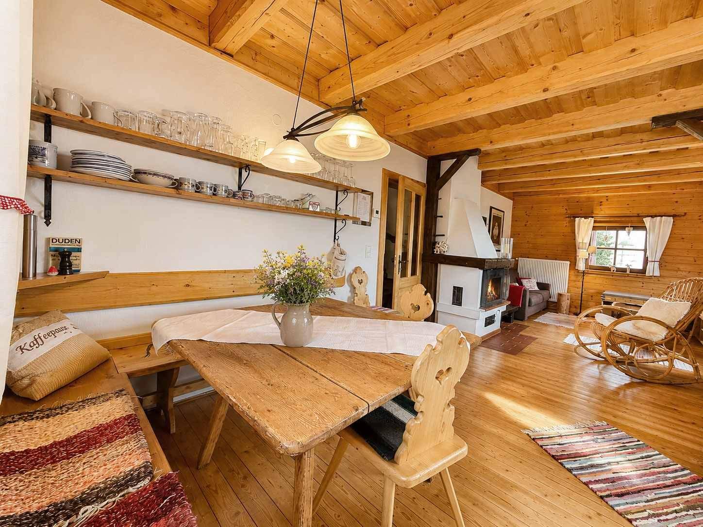 Rustikaler Wohn- und Essbereich mit Holzbalken, Kamin und traditionellen Holzmöbeln im Landhausstil.