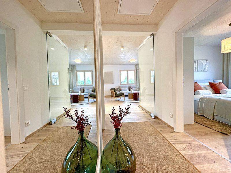 Heller Flur mit Holzboden und Spiegeltüren, die den Wohnbereich reflektieren.