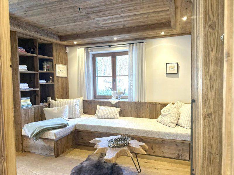 Gemütliche Sitzecke mit Holzeinbauten, Bücherregal und weichen Kissen, ideal zum Entspannen.