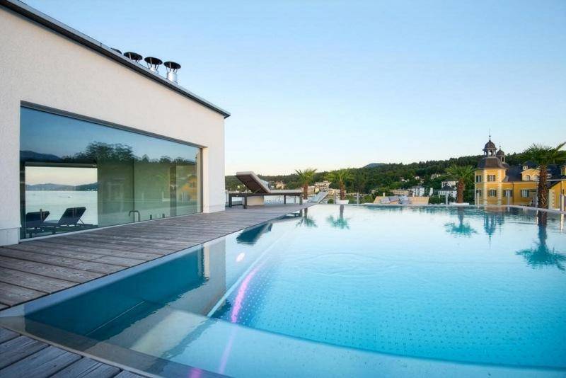 Infinity-Pool auf einer Holzterrasse mit Blick auf den See und die umliegende Landschaft.