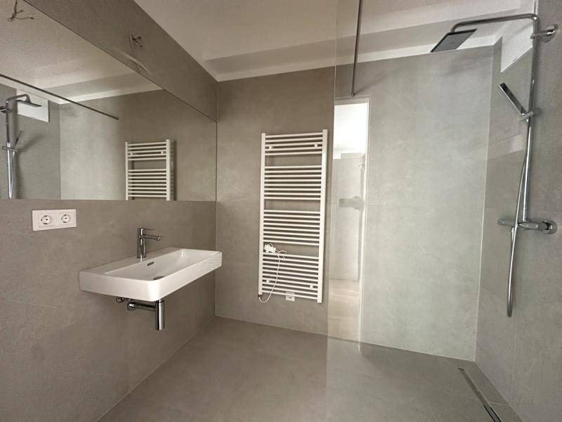 Modernes Badezimmer mit begehbarer Dusche, elegantem Waschbecken und beheiztem Handtuchhalter.