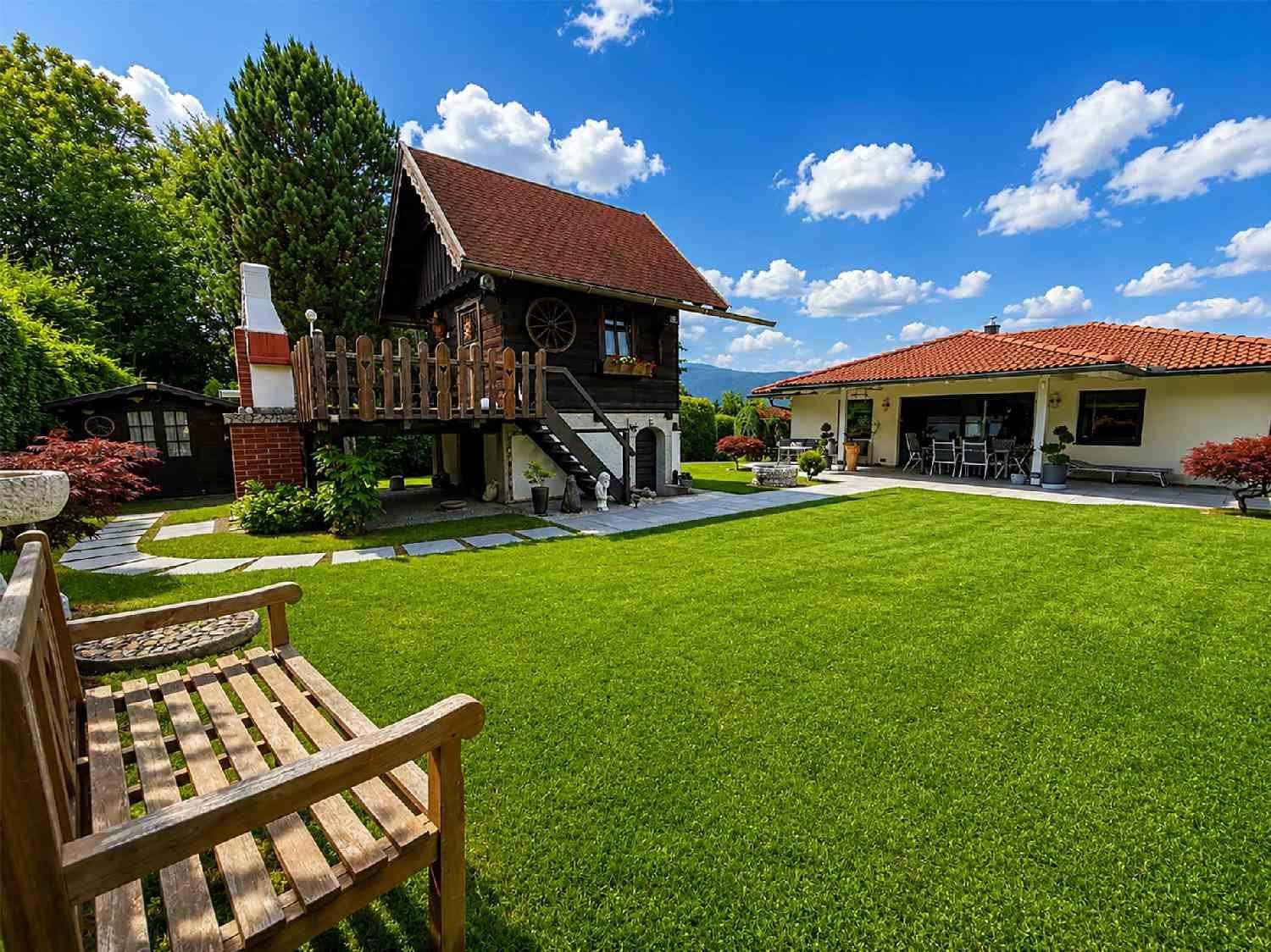 Weitläufiger Garten mit Haupthaus, charmantem Holzhaus und Sitzbank.