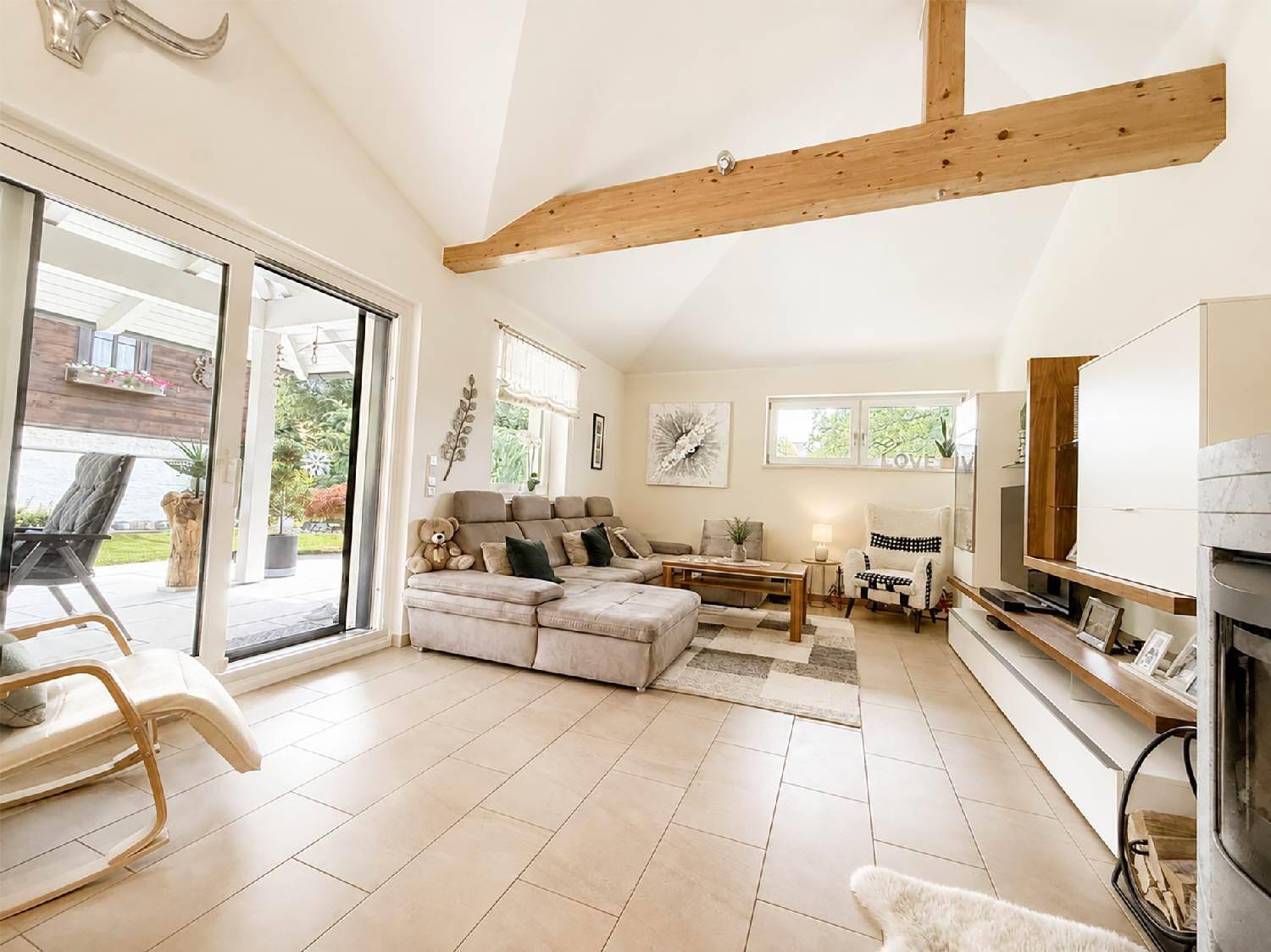 Helles Wohnzimmer mit hohen Decken, Holzbalken und Zugang zur Terrasse.