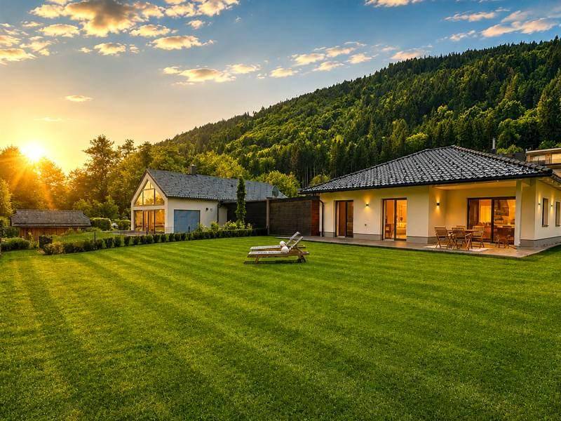 Weitläufiger Garten mit zwei Häusern und malerischem Sonnenuntergang über den Bergen.