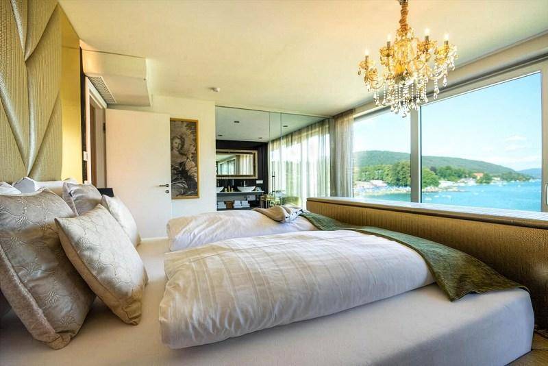 Elegantes Schlafzimmer mit großen Fenstern, Kronleuchter und direktem Seeblick.