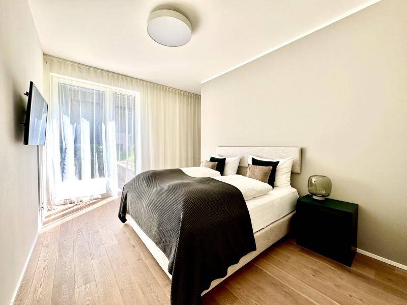 Helles Schlafzimmer mit Holzboden, modernem Bett und großen Fenstern für viel Tageslicht.