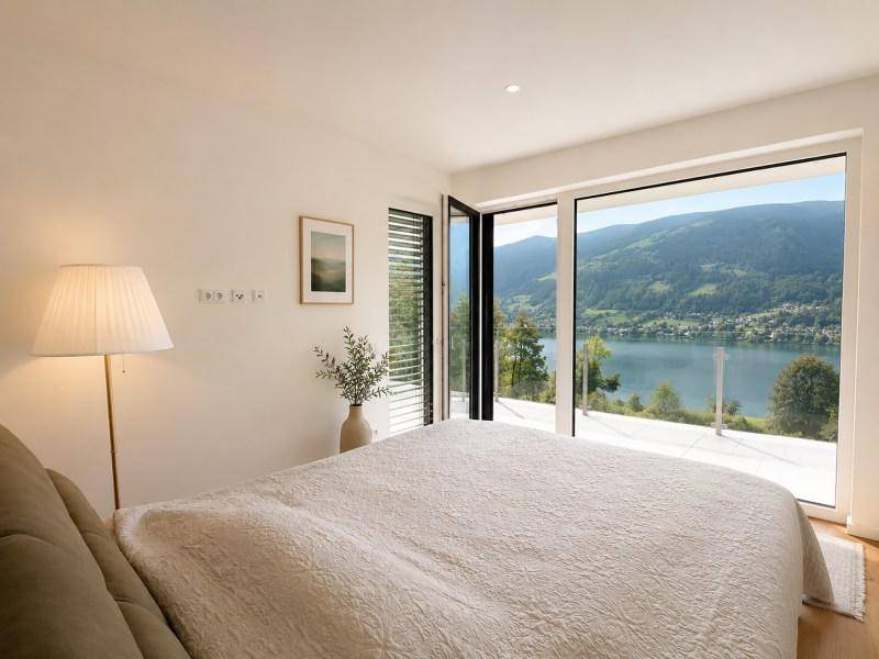 Schlafzimmer mit großem Bett, Holzboden und raumhohen Fenstern mit atemberaubendem Seeblick.