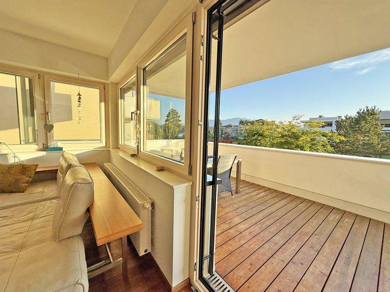 Gemütlicher Balkon mit Holzboden und Blick auf die grüne Umgebung.
