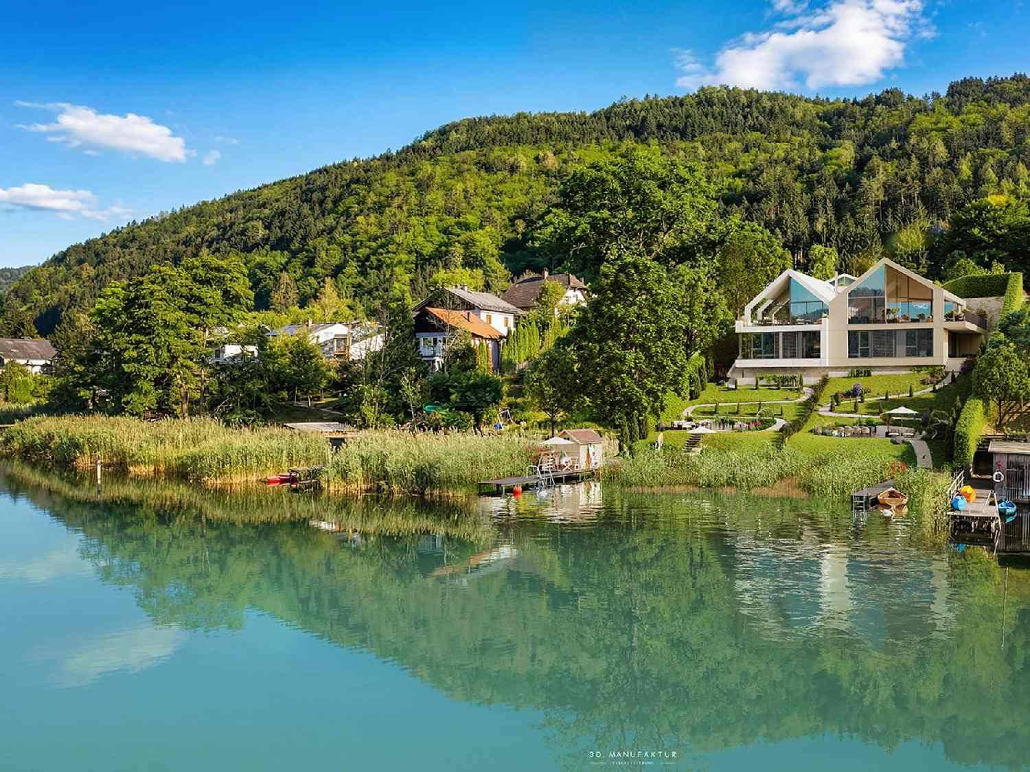 Moderne Villa am See mit terrassiertem Garten, umgeben von üppiger grüner Landschaft und Bergen.