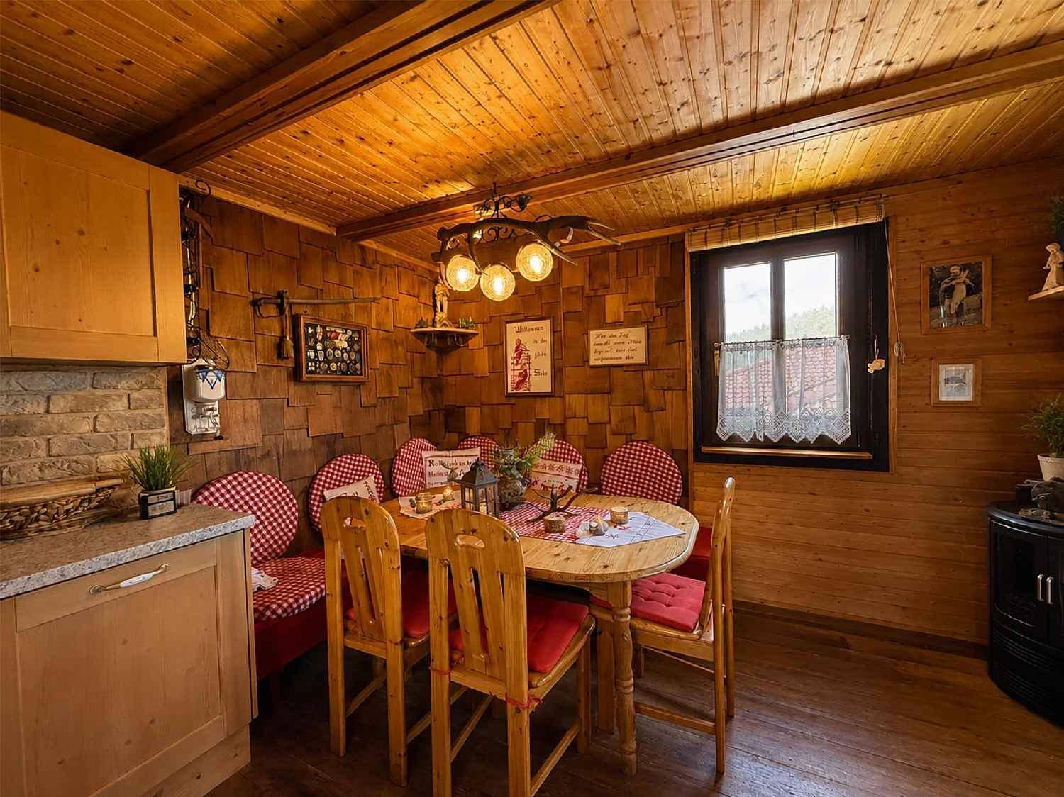 Rustikaler Essbereich mit Holztisch, karierten Sitzpolstern und Holzvertäfelung.