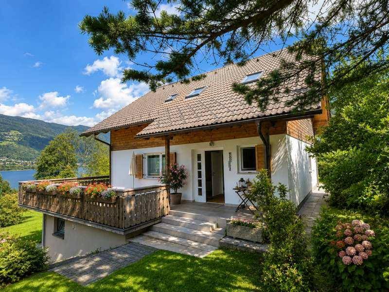 Attraktives Haus mit Balkon, gepflegtem Vorgarten und Blick auf den See und die Berge.