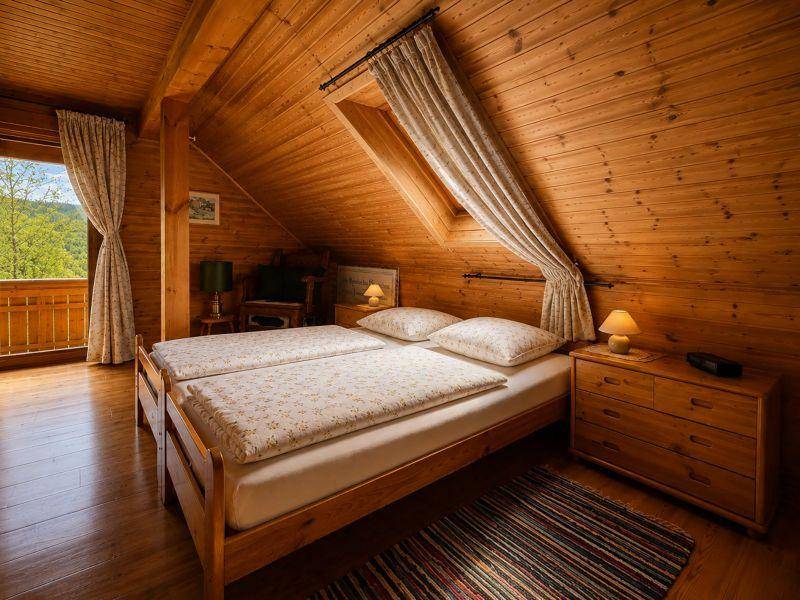 Gemütliches Schlafzimmer im Dachgeschoss mit Holzvertäfelung, schrägen Decken und Balkonzugang.