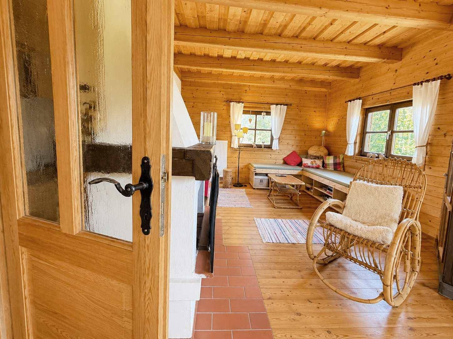 Gemütliches Wohnzimmer im Landhausstil mit Holzwänden, Kamin und Korbsessel.