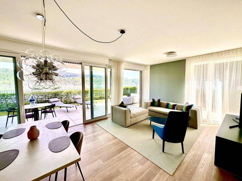 Heller Wohn-Essbereich mit Holzboden, modernen Möbeln und Zugang zur Terrasse mit Seeblick.