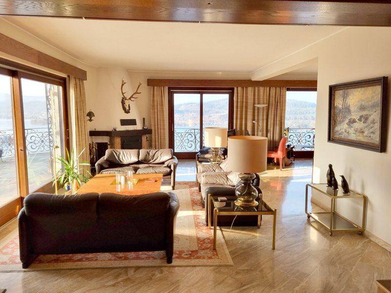 Geräumiges Wohnzimmer mit Ledersofas, Marmorboden und großen Fenstern mit Seeblick.
