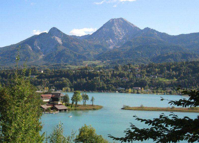 Panoramablick auf die majestätischen Berge und den glitzernden See, umgeben von grünen Wäldern.