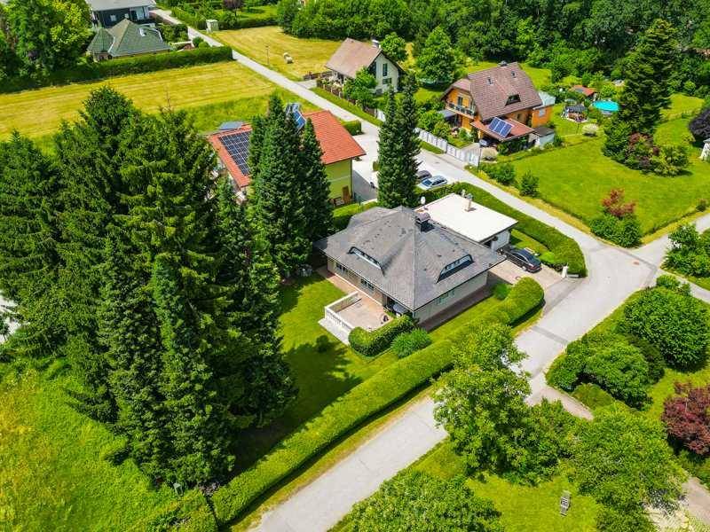 Vogelperspektive eines Hauses mit großem Garten und umliegender Naturlandschaft.