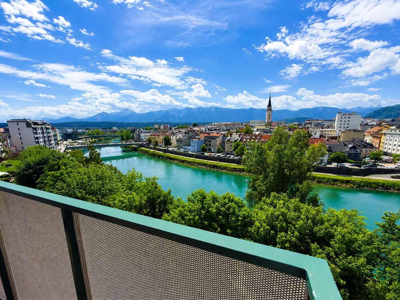 Weitläufiger Blick vom Balkon über die Stadt, den Fluss und die majestätische Berglandschaft.