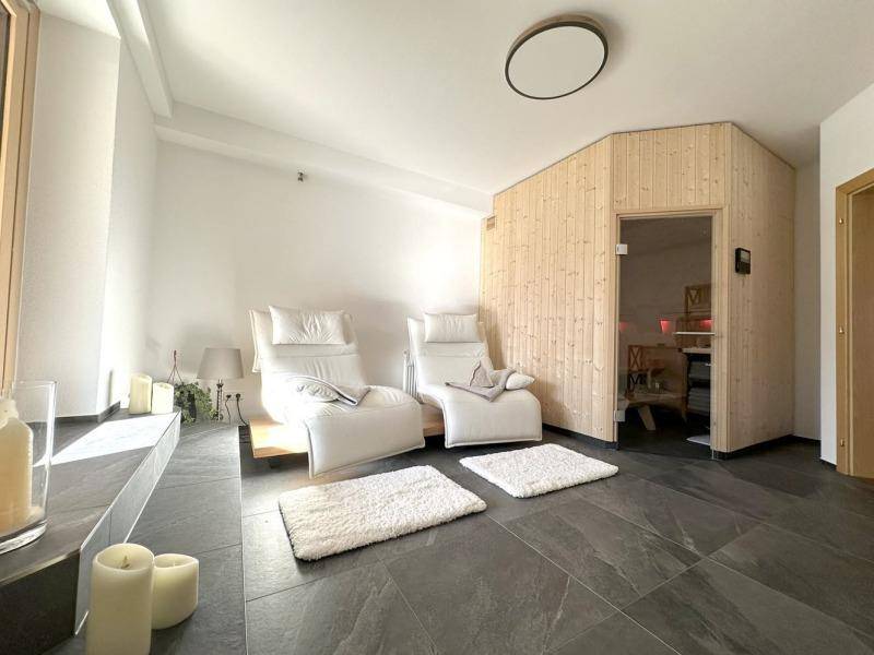 Entspannender Wellnessbereich mit bequemen Liegen und Zugang zu einer modernen Sauna.