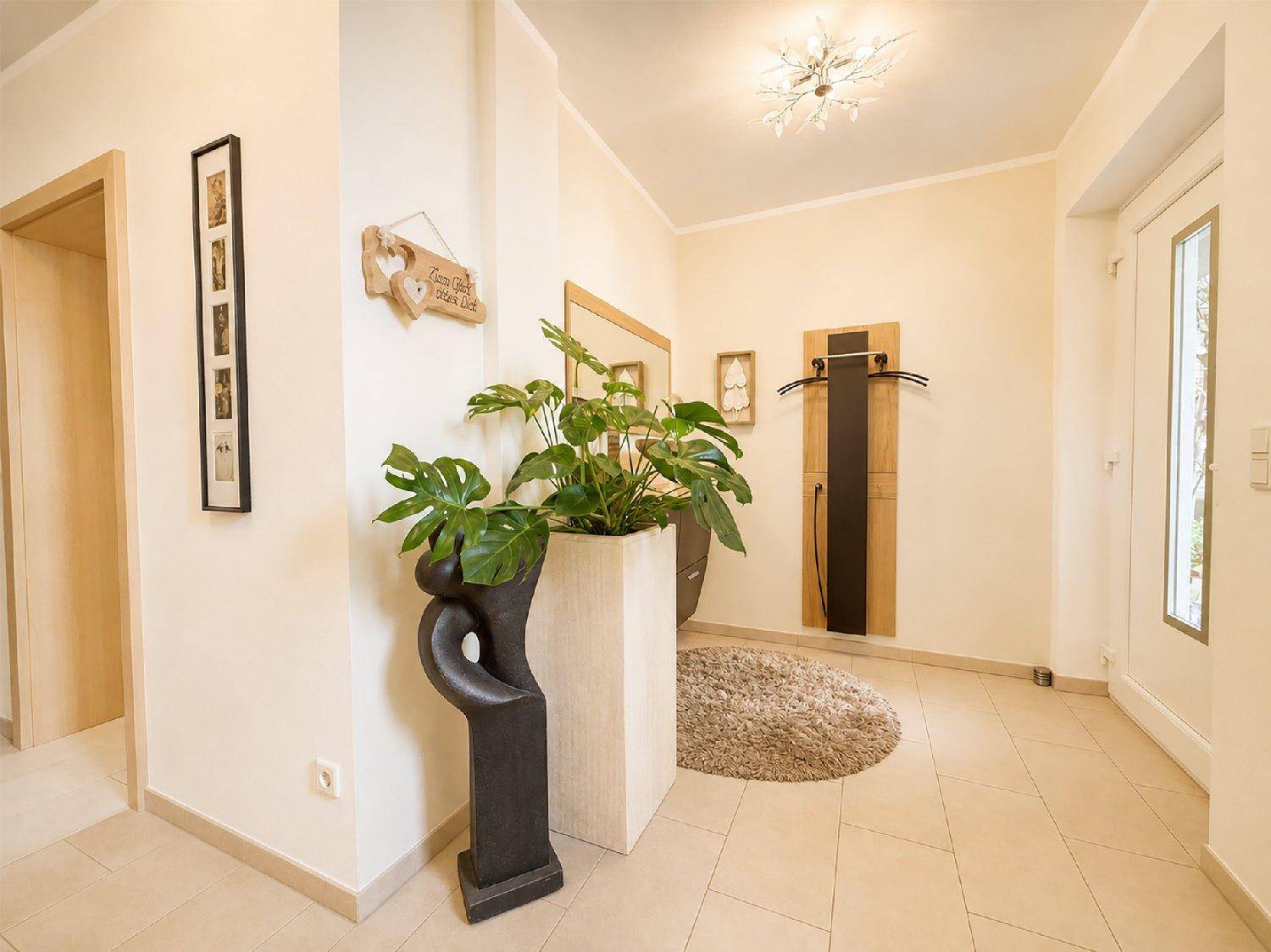 Heller Eingangsbereich mit Fliesenboden, Garderobe und dekorativen Pflanzen.